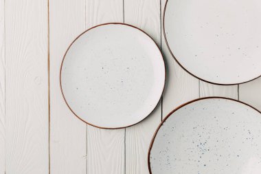 Ceramic glazed plates on white wooden background clipart