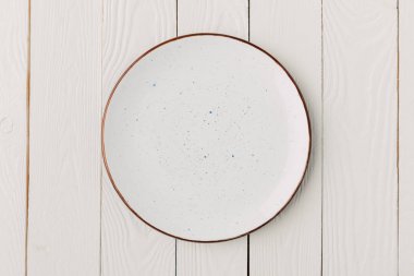 Ceramic glazed plate on white wooden background clipart