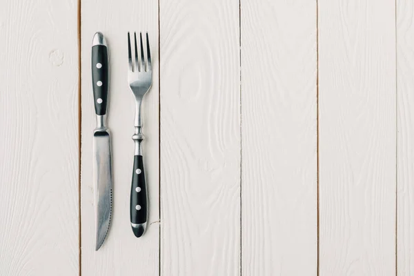 白い木製の背景にフォークとナイフのトップ ビュー — ストック写真
