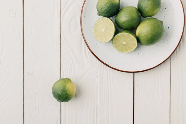 Ovanifrån Plattan Med Gröna Limefrukter Vit Trä Bakgrund — Stockfoto