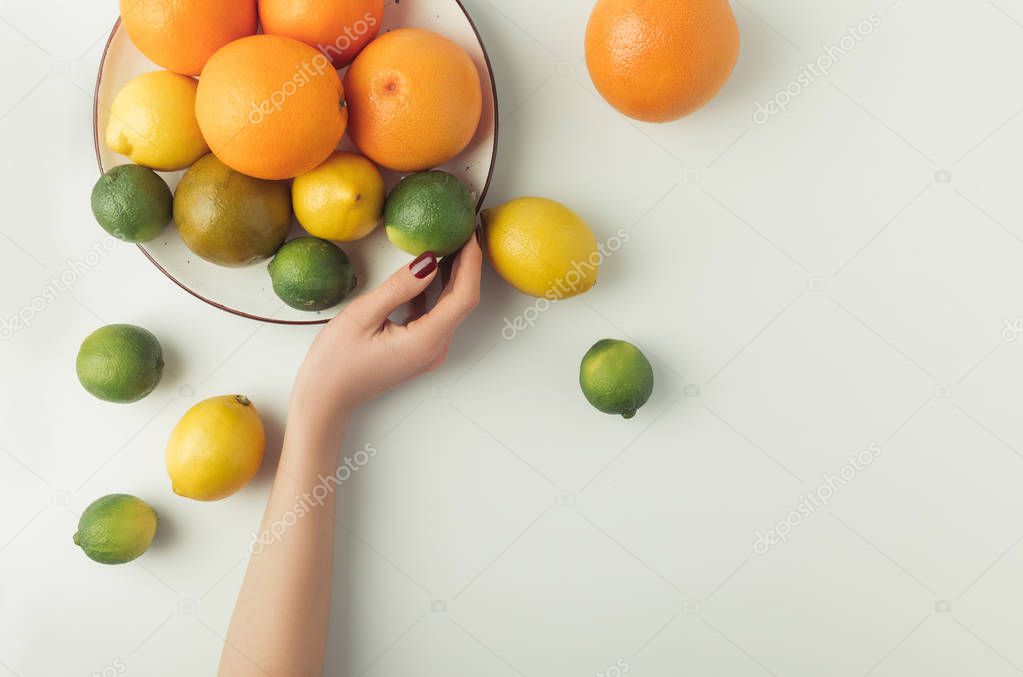 Woman holding plate with citrus fruits isolated on white background