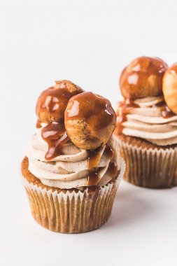 krema, profiterol ve üzerinde beyaz izole karamel ile cupcakes görünümünü kapat