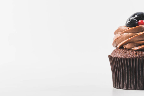 Закрыть вид на шоколадный кекс со сливками, ягодами и сливой изолированы на белом
