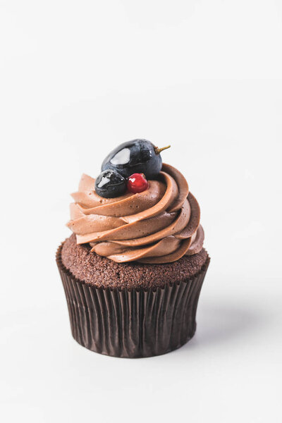 close up view of chocolate cupcake with cream, berries and plum isolated on white