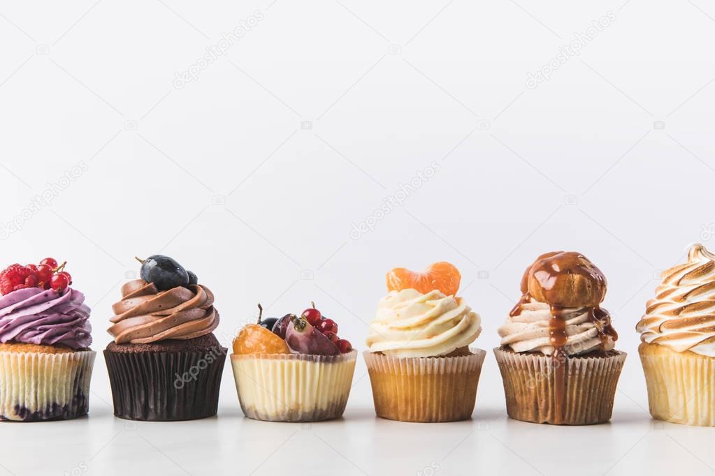 close up view of various sweet cupcakes isolated on white