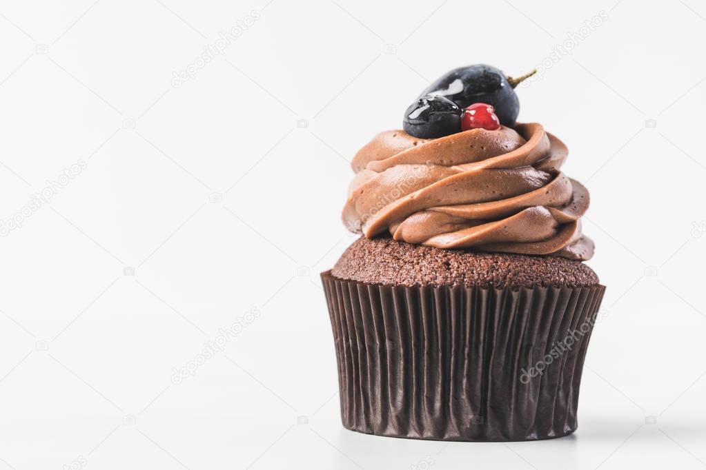close up view of chocolate cupcake with cream, berries and plum isolated on white