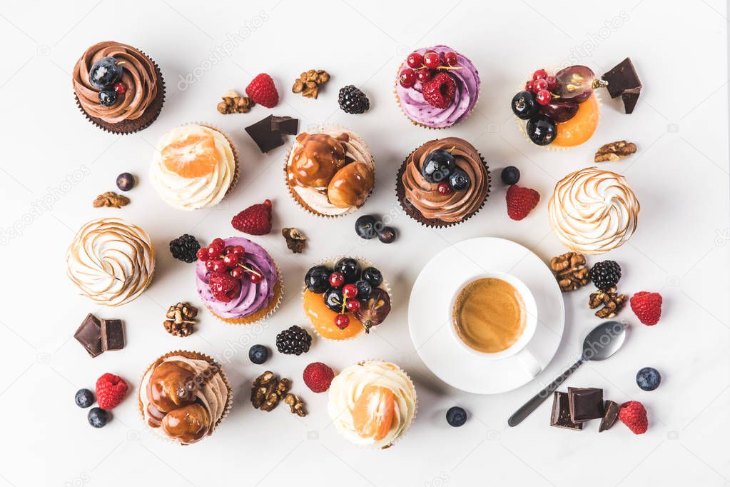 flat lay with arrangement of sweet cupcakes, teaspoon and cup of coffee isolated on white