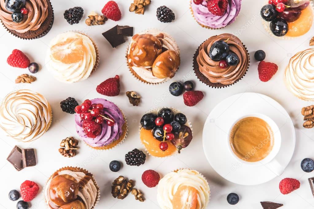 flat lay with cup of coffee, sweet cupcakes, berries, chocolate pieces and hazelnuts isolated on white