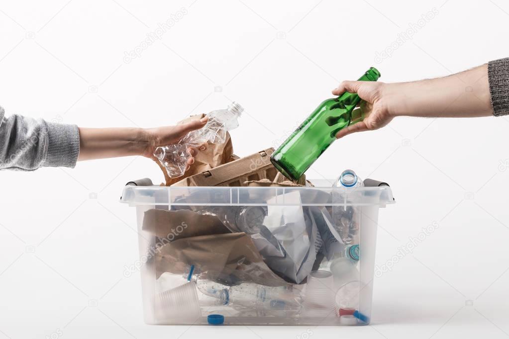 cropped shot of people putting trash into plastic container isolated on white, recycling concept