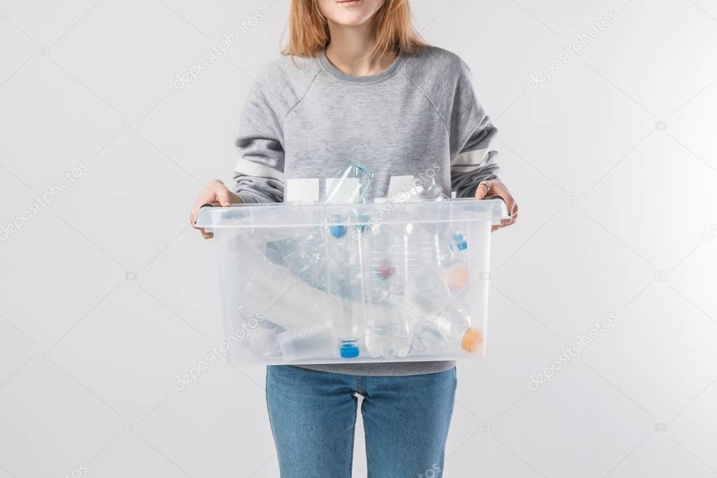 partial view of woman holding container with plastic bottles isolated on grey, recycle concept