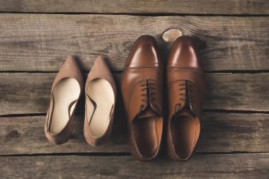 top view of bridal and grooms pairs of shoes on wooden surface clipart