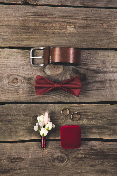 flat lay with arranged grooms accessories and wedding rings on wooden tabletop