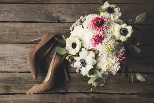 flat lay with bridal shoes and beautiful bouquet on wooden tabletop