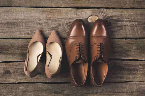 top view of bridal and grooms pairs of shoes on wooden surface