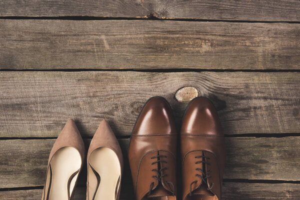 top view of bridal and grooms pairs of shoes on wooden surface