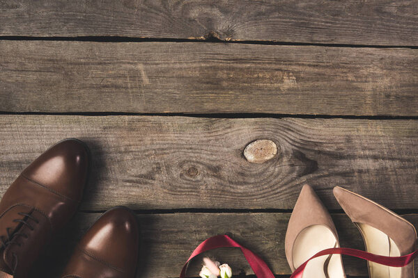 flat lay with ribbon, corsage, bridal and grooms shoes on wooden tabletop