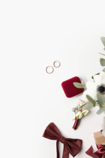 плоский лежал с обручальными кольцами, пуговица, галстук-бабочка и ювелирная коробка изолированы на белом
