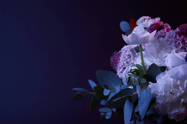 bouquet of different flowers and green leaves on dark