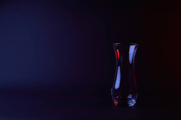 empty glass vase with reflection on dark surface 