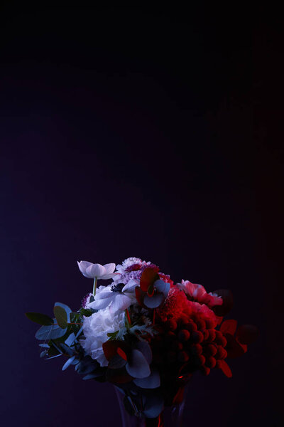 bouquet of different white flowers with red light on dark