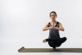 Frau übt Zehenstand auf Yogamatte isoliert auf weiß