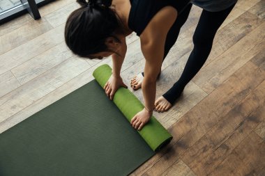 high angle view of girl putting yoga mat on floor  clipart