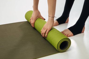 cropped image of woman putting yoga mat on floor