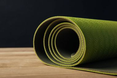 Yeşil haddelenmiş yoga mat siyah ahşap masa üstü