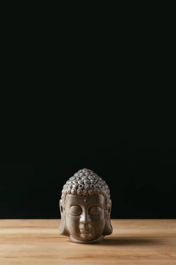 Sculpture of buddha head on wooden table clipart