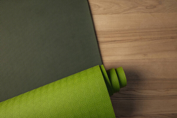 top view of green yoga mat on brown floor