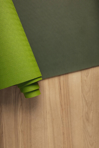 top view of green yoga mat on wooden brown floor
