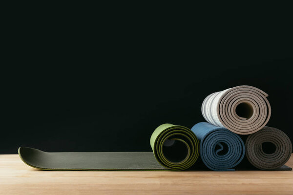 different colored rolled yoga mats on wooden table