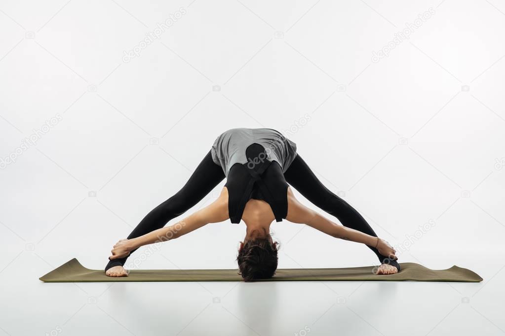 woman practicing yoga and doing wide legged forward fold