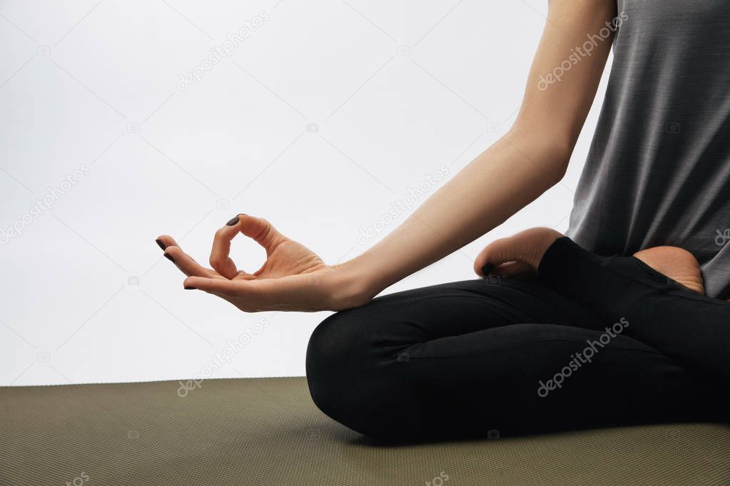 cropped image of woman meditating in yoga lotus pose isolated on white