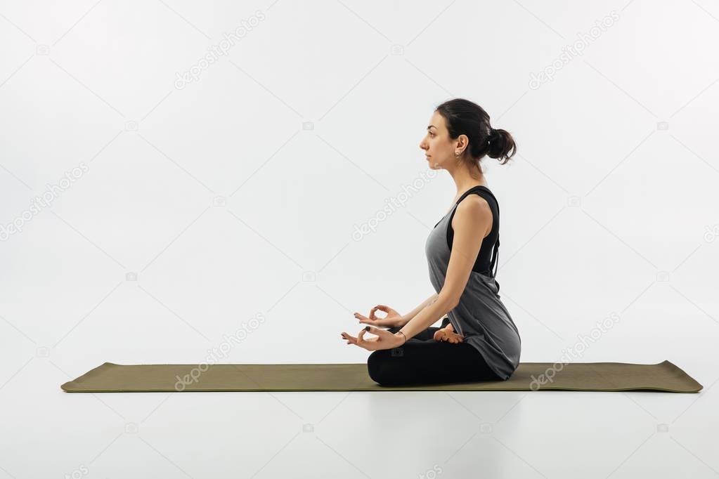 side view of woman meditating in yoga lotus pose isolated on white