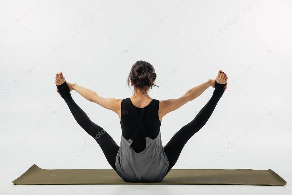 rear view of woman practicing yoga asana urdhva upavistha konasana isolated on white