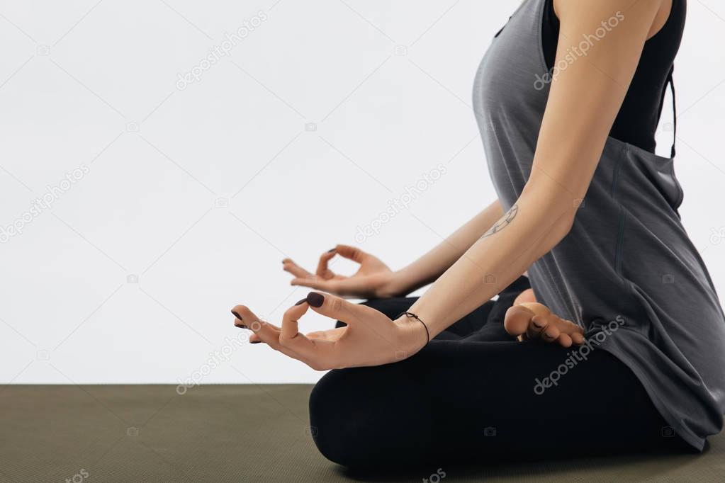 cropped image of woman meditating in yoga lotus pose isolated on white