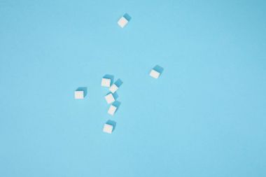 top view of sweet white tasty sugar cubes with shadows on blue clipart