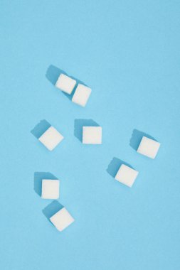 close-up view of sweet white tasty sugar cubes on blue clipart