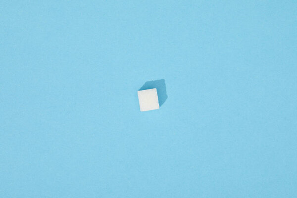 sweet white sugar cube with shadow on blue 