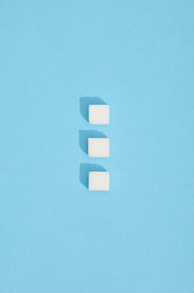 sweet white sugar cubes with shadows on blue 