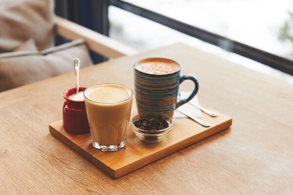 Coffee drinks with beans and orange peel on table in cafe