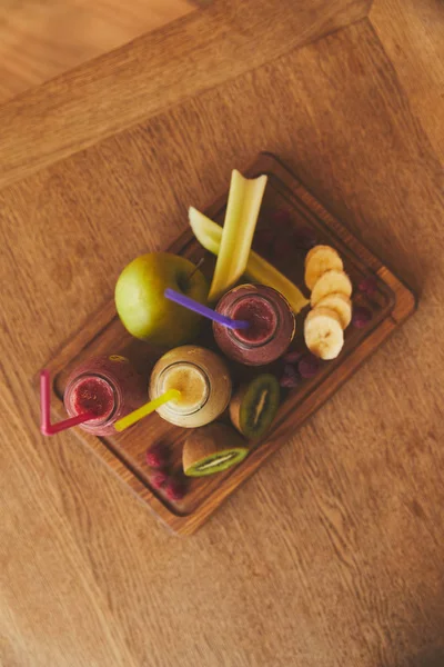 生の果物や木の板でスムージーとボトル  — 無料ストックフォト