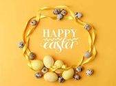 pohled shora žluté malovaná velikonoční vajíčka a křepelčích vajec na žluté s nápisem happy easter