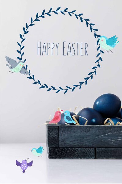 blue painted easter eggs in box with drawn birds and happy easter lettering