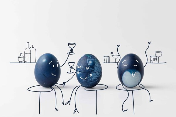 three blue painted easter eggs with drawn faces drinking at bar on white surface