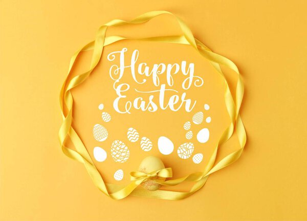top view of yellow painted easter egg with ribbons on yellow with happy easter lettering