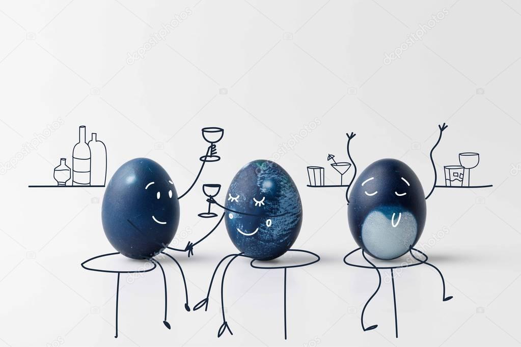 three blue painted easter eggs with drawn faces drinking at bar on white surface