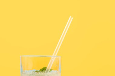 close-up view of glass with fresh cold summer cocktail and drinking straw isolated on yellow clipart