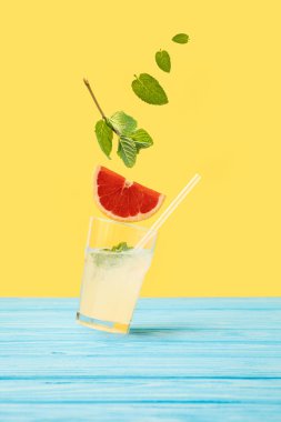 ingredients falling in glass with fresh cold summer cocktail on yellow clipart